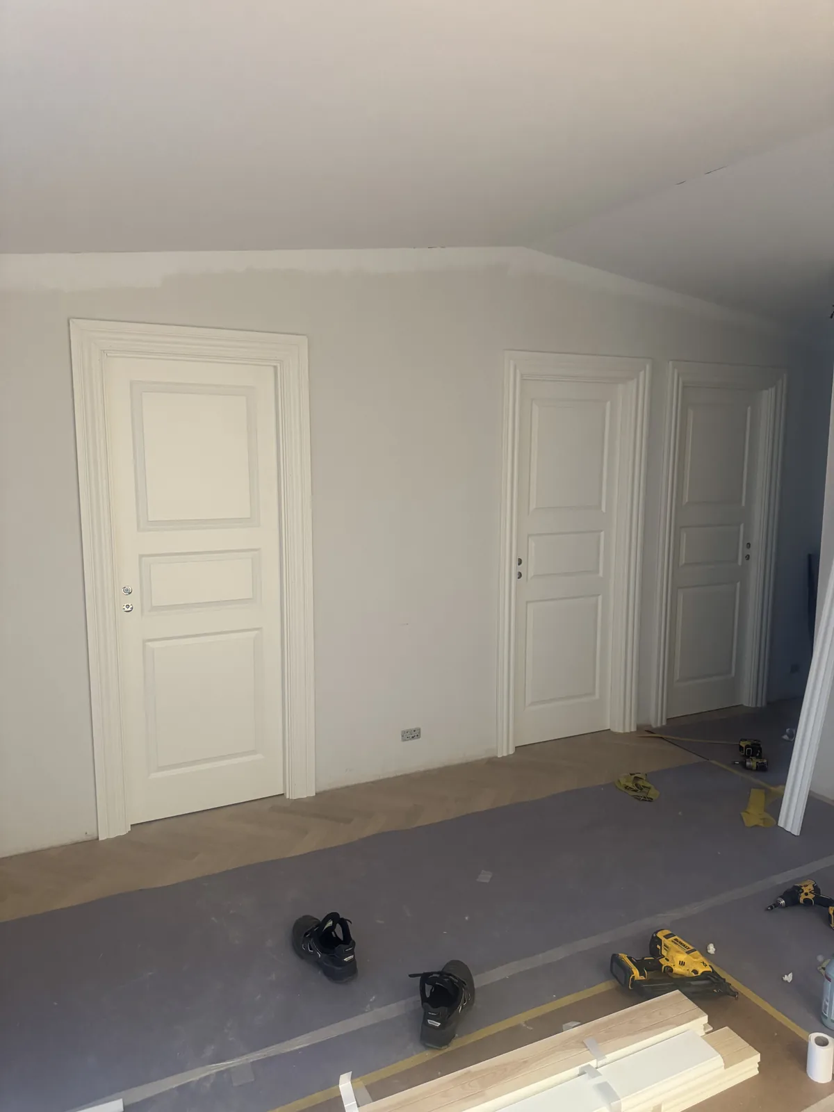 Tre hvide indvendige døre med profilerede indfatninger under renovering