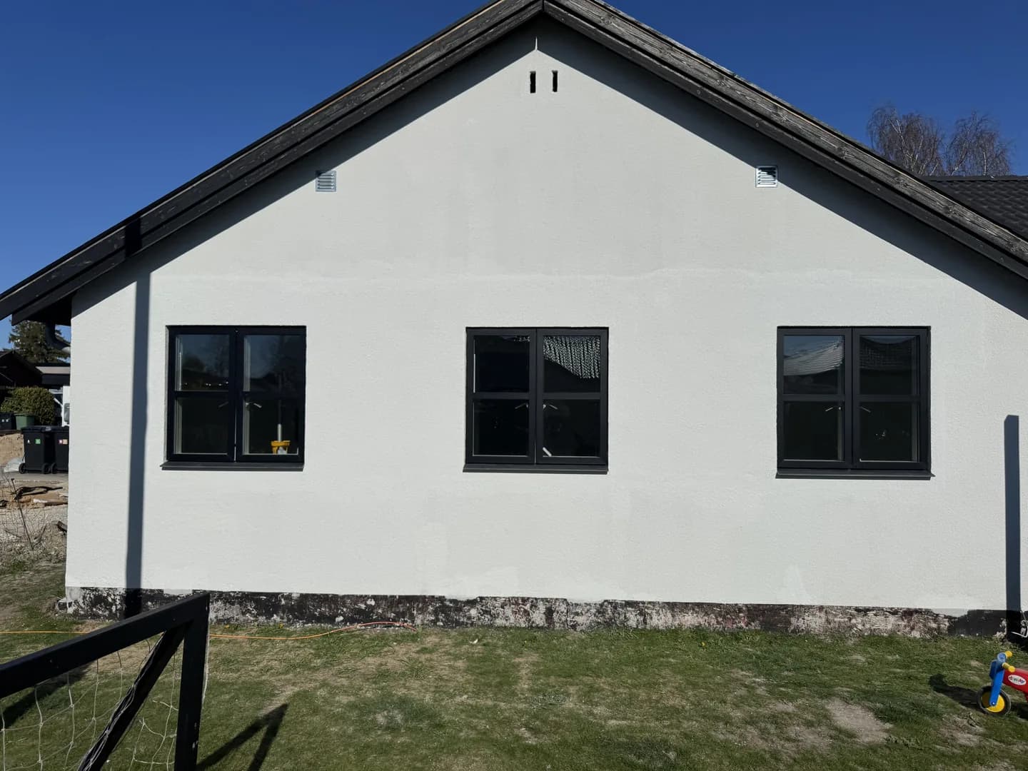 Tre mørke vinduer i en hvid gavl